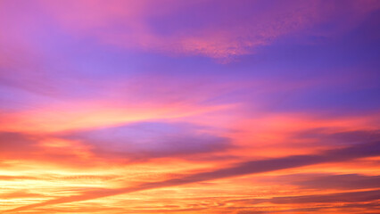 Evening sky background after sundown with colorful yellow and orange sunlight clouds on blue dusk sky in widescreen view