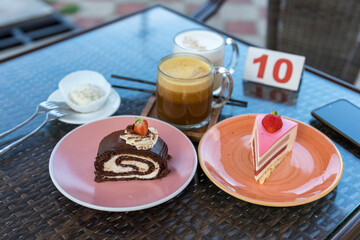 A table with a variety of desserts including a chocolate roll, a strawberry cake