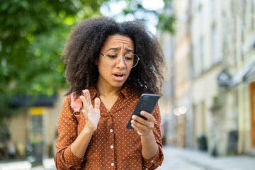 Worried woman using phone outdoors to check message with concerned expression