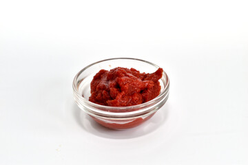 On a white background, tomato paste in a glass round plate.