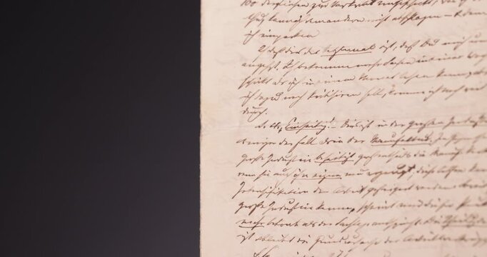 Detailaufnahme Rotation eines alten und mit romantischer Schrift verfassten Briefes vor schwarzem Hintergrund