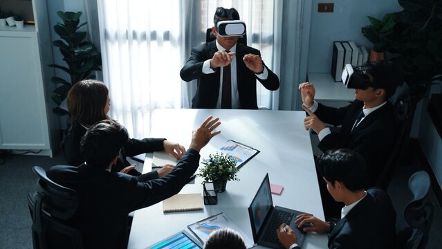 Top view of manager working on laptop and sending data analysis to business people by using VR glass headset while diverse team planning marketing strategy and looking at financial graph. Directorate.