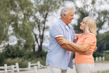 Obraz premium Happy Senior Couple Embracing Outdoors in a Park on a Sunny Day