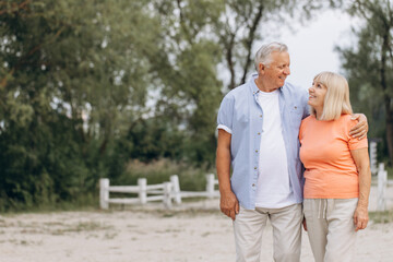 Obraz premium Happy Elderly Couple Enjoying a Walk in Nature on a Sunny Day