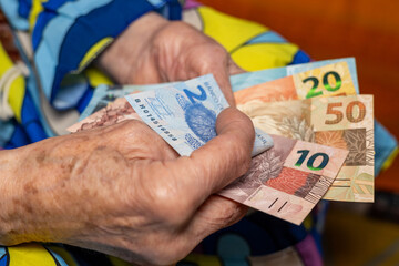 Pensioner's finances. An old lady counts Brazilian money, Pension in Brazil.