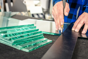 A glazier cuts thick glass by hand using a hand cutter. Glass work