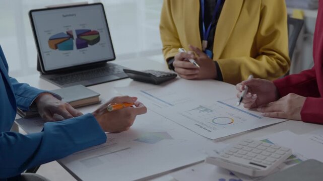 Diverse team discussing financial charts and graphs in a modern office. Collaborative business meeting focused on data analysis and project planning