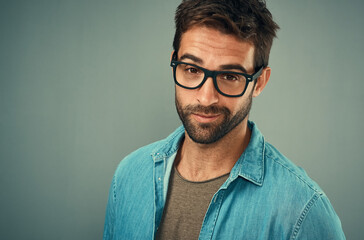 Obraz premium Portrait, man and glasses in studio for vision, prescription and confidence with pride for clear eyesight. Product, eyewear frame and male person with spectacle for eye care and gray background