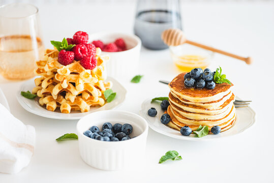 Summer breakfast. Homemade baked ricotta pancakes and Belgian waffles with fresh berries on white wooden table