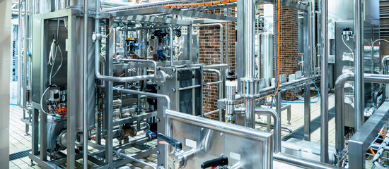 Modern brewery with extensive stainless steel piping and tanks, sophisticated technology used in beer production.