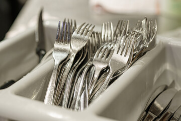 Clean spoons, forks and knives in the kitchen in a cafe. Cutlery in a restaurant.