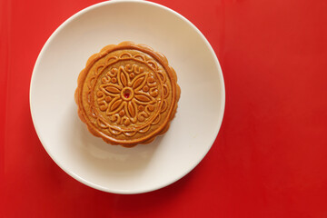 Top view of mooncake on a white plate, tradition chinese mooncake on red background. Mid Autumn celebration, Happy Chinese translation Mid Autumn festival.