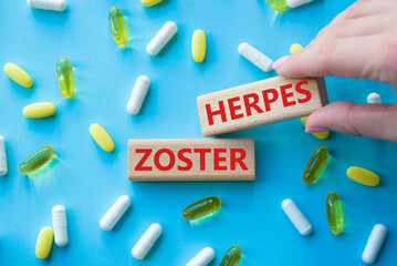 Herpes Zoster symbol. Concept word Herpes Zoster on wooden blocks. Beautiful blue background with pills. Doctor Hand. Medicine and Herpes Zoster concept. Copy space