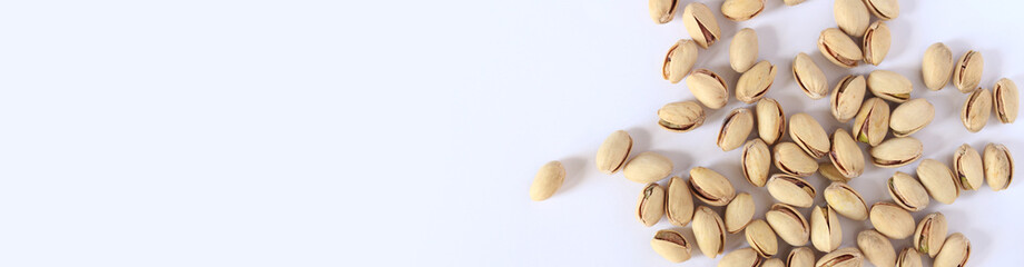 Pistachios on a white background. A handful of dry salted pistachios on a light background, selective focus. Pistachio with shell. Close-up