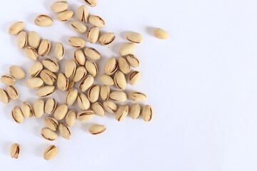 Pistachios on a white background. A handful of dry salted pistachios on a light background, selective focus. Pistachio with shell. Close-up