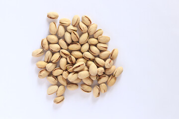 Pistachios on a white background. A handful of dry salted pistachios on a light background, selective focus. Pistachio with shell. Close-up
