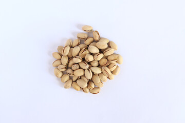 Pistachios on a white background. A handful of dry salted pistachios on a light background, selective focus. Pistachio with shell. Close-up