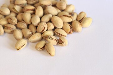 Pistachios on a white background. A handful of dry salted pistachios on a light background, selective focus. Pistachio with shell. Close-up