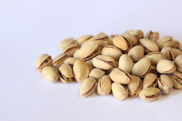 Pistachios on a white background. A handful of dry salted pistachios on a light background, selective focus. Pistachio with shell. Close-up