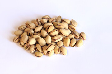 Pistachios on a white background. A handful of dry salted pistachios on a light background, selective focus. Pistachio with shell. Close-up