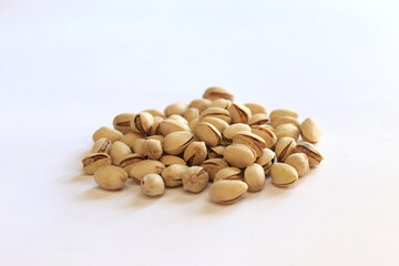 Pistachios on a white background. A handful of dry salted pistachios on a light background, selective focus. Pistachio with shell. Close-up