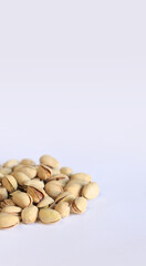 Pistachios on a white background. A handful of dry salted pistachios on a light background, selective focus. Pistachio with shell. Close-up
