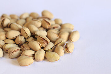 Pistachios on a white background. A handful of dry salted pistachios on a light background, selective focus. Pistachio with shell. Close-up