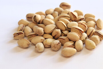 Pistachios on a white background. A handful of dry salted pistachios on a light background, selective focus. Pistachio with shell. Close-up