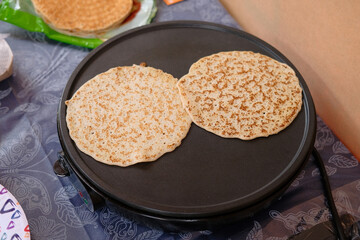 Two pancakes on a hot electric pancake maker. Pancake making process.