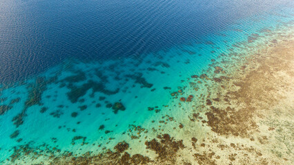 Aerial drone view of the shallow coral reef and azure blue south pacific ocean water at Araarapupu point on the tropical island of Bora Bora. 