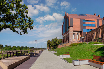 Malbork, Poland - a promenade along the Nogat River near the Teutonic Castle, on the right the rebuilt municipal public library in the former Latin school