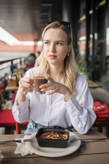 Blonde gen z woman eating lasagna in the cafe on break. Gen z girl spend time in restaurant