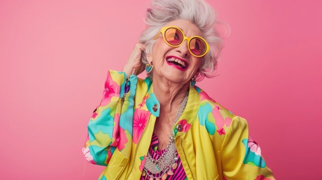 Happy senior woman in colorful neon outfit, funny sunglasses and extravagant style, laughing and smiling, trendy grandma posing in studio
