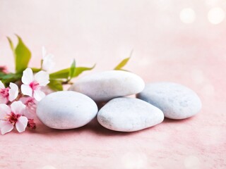 Soft white stones arranged with delicate pink flowers on a light background