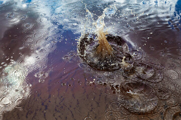 Obraz premium Close-up view of a splash in water, surrounded by concentric ripples and reflections of the sky. The dynamic movement of the splash contrasts with the calm ripples, creating an energetic 