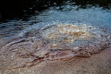 Close-up view of a splash in water, surrounded by concentric ripples and reflections of the sky. The dynamic movement of the splash contrasts with the calm ripples, creating an energetic 