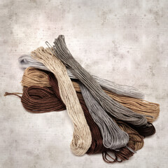 textured stylish old paper background, square, with cotton embroidery thread hanks in different...