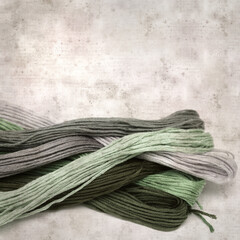 textured stylish old paper background, square, with cotton embroidery thread hanks in different...