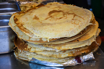 A stack of freshly made golden-brown crepes for selling at food market during Shrovetide celebration