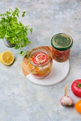 Salad sliced ​​fast pickled tomatoes with onions in a glass jar on a gray concrete background. Harvesting, conservation, pickled vegetables.