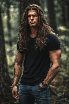 A muscly handsome man wearing jeans and a black t-shirt with long hair.