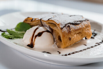 Dessert strudel with chocolate and ice cream on a white plate