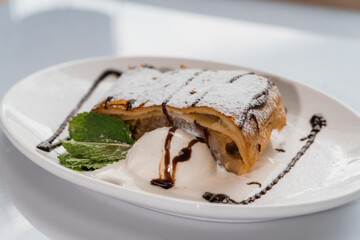Dessert strudel with chocolate and ice cream on a white plate
