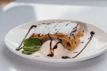 Dessert strudel with chocolate and ice cream on a white plate