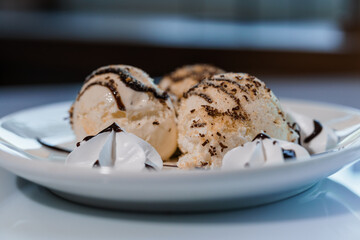 Ice cream with fruits and chocolate on a white plate