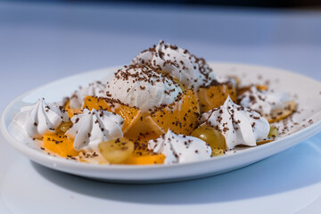 Ice cream with fruits and chocolate on a white plate