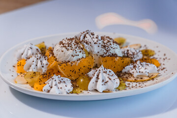 Ice cream with fruits and chocolate on a white plate