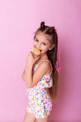 Happy little girl eating ice cream in a cone on a pink background. So yummy. Closeup photo of beautiful funny little lady. A child holds ice cream in his hand in a cup on a pink background.