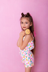Happy little girl eating ice cream in a cone on a pink background. So yummy. Closeup photo of beautiful funny little lady. A child holds ice cream in his hand in a cup on a pink background.