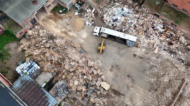 Drone footage of a telehandler removing wooden pallet from a truck during summer day